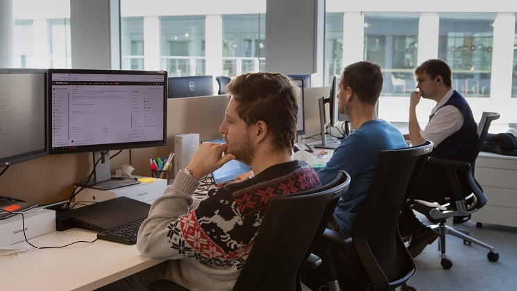 Three people sitting by their computers